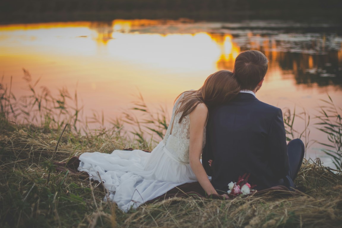 Couple sitting by the lake in wedding attire